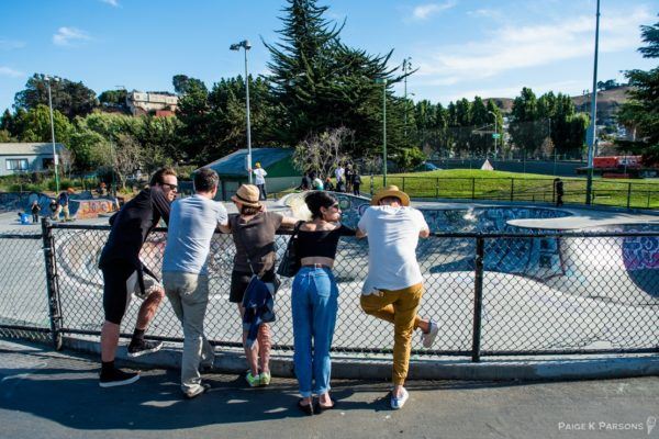 People Leaning on Fence by Skate Park