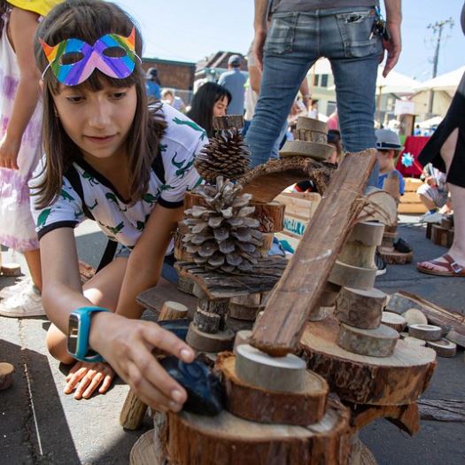 Kids building with pieces of wood, sticks, and pine cones