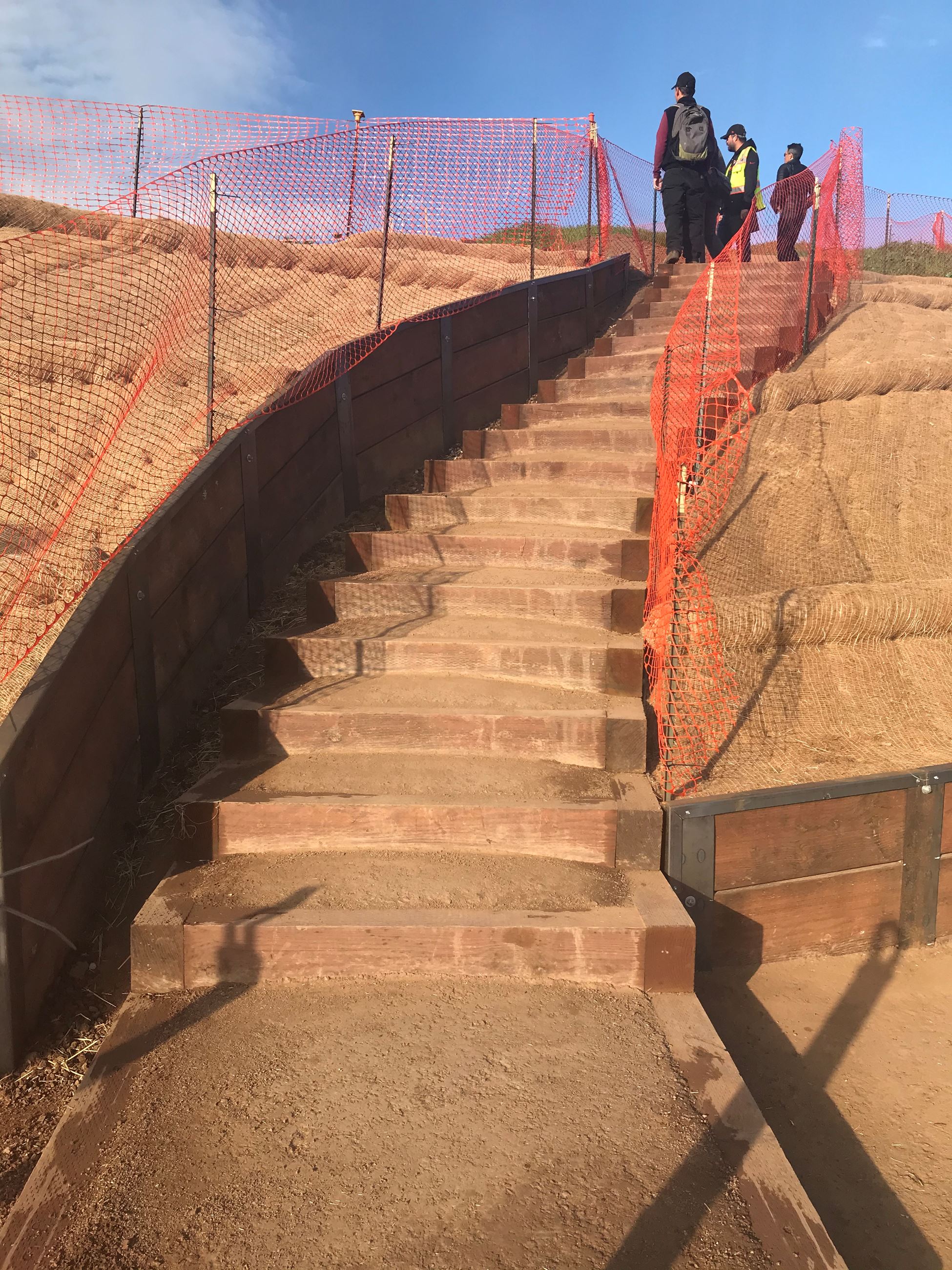 View of Box Steps Up Bernal Hill with orange construction fencing and crew standing at the top of th