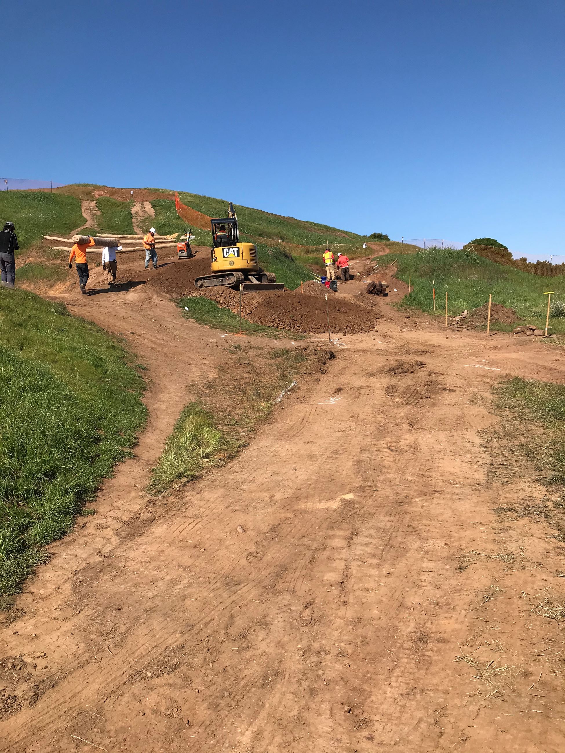 View of dirt trail at Bernal Heights with orange construction fencing and construction crew in the b