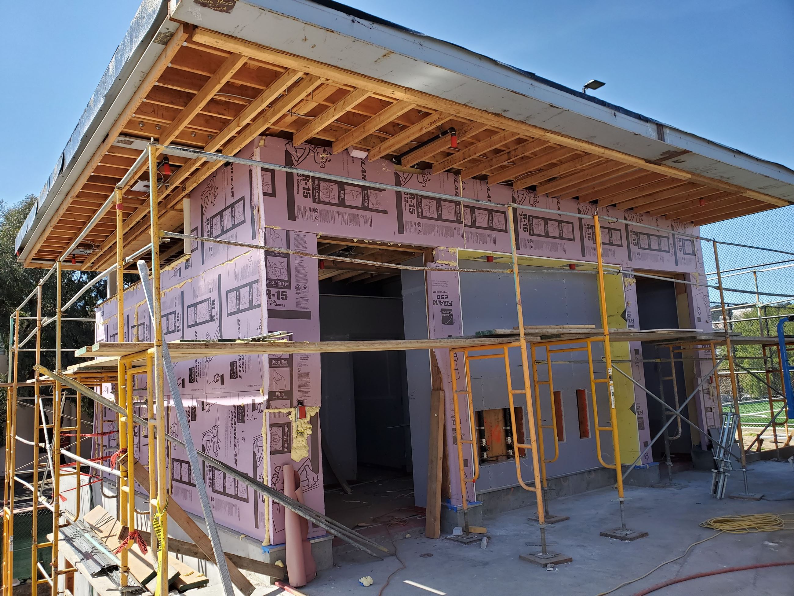 Photo is of the restroom being sealed with pink building wrap with scaffolding surrounding the struc