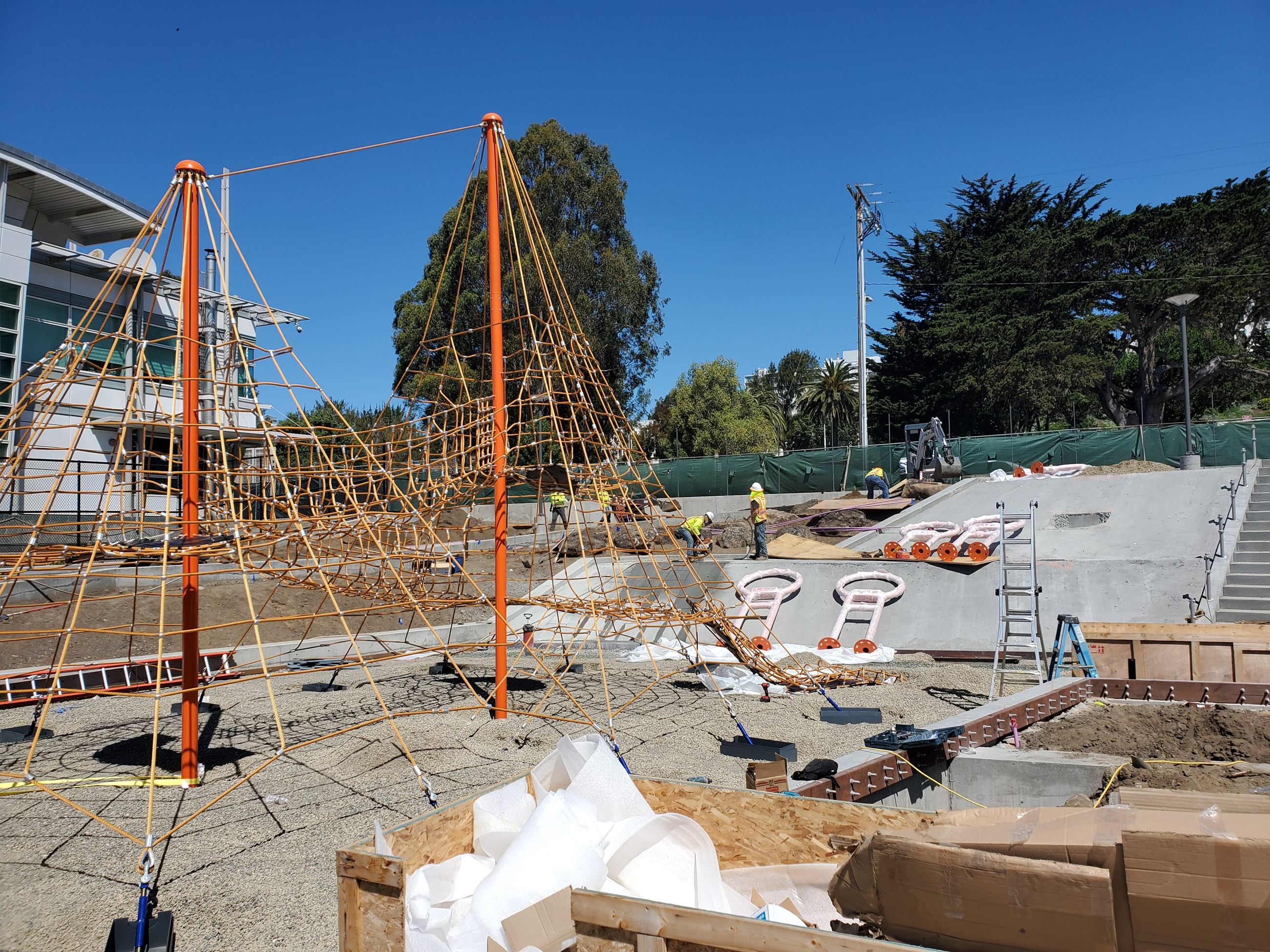 Margaret Hayward red playground structure being newly installed. The structure is centered on gravel