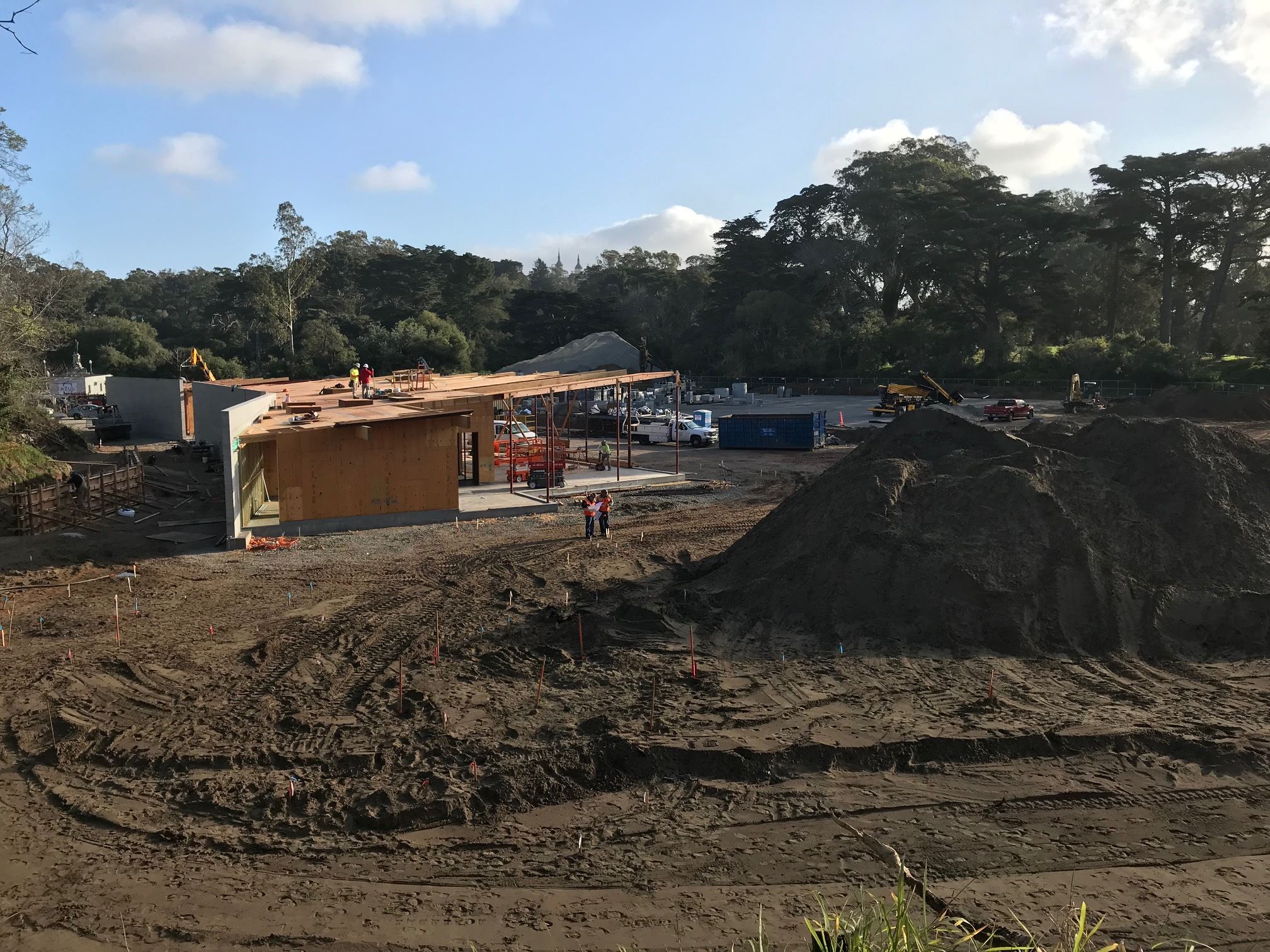 Image shows the tennis center clubhouse to the left and constructiion equipment and materials in the