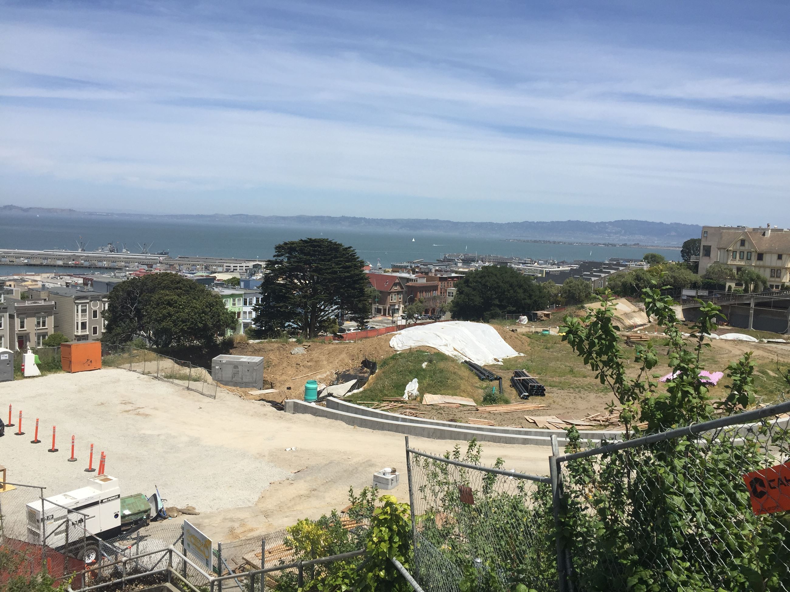 Image is looking down on the site. A flat dirt area is pictured on the left and is lined by orange c