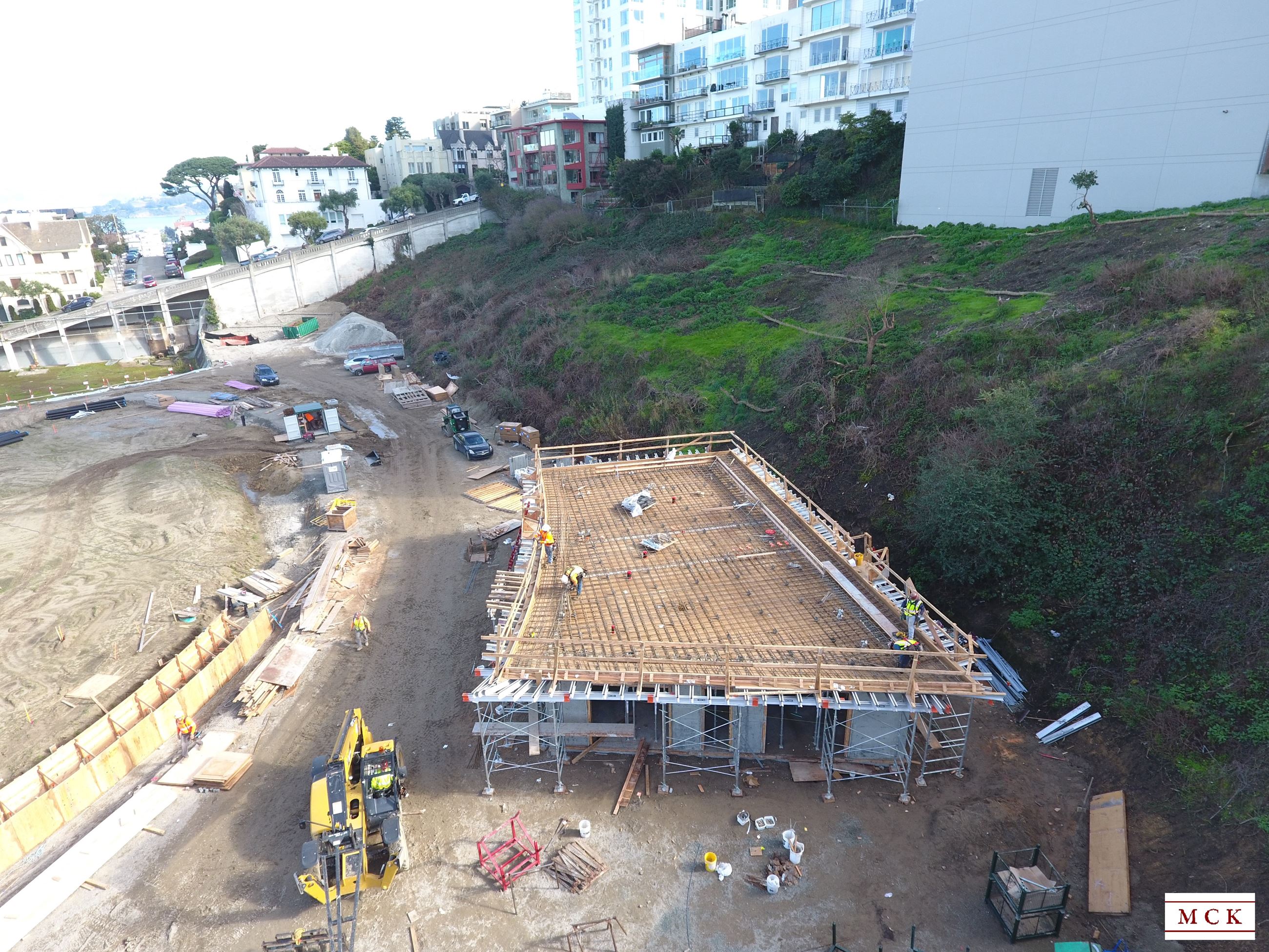 Image shows the convenience building with bathroom entrance showing, four workers wearing orange saf