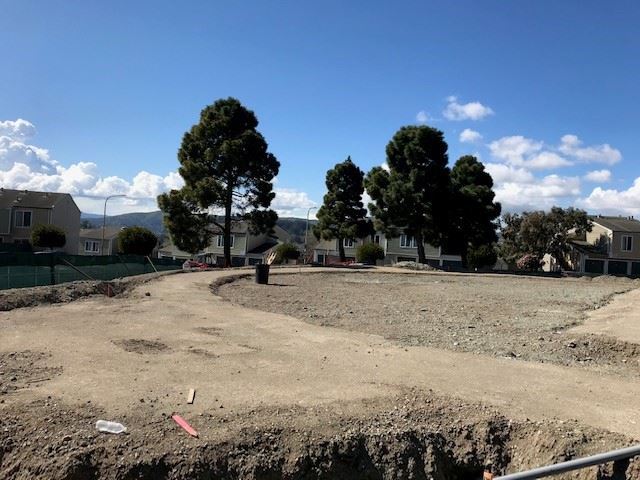 Shoreview Park circular dirt path by the unplanted lawn area. A black garbage can is on the right ha