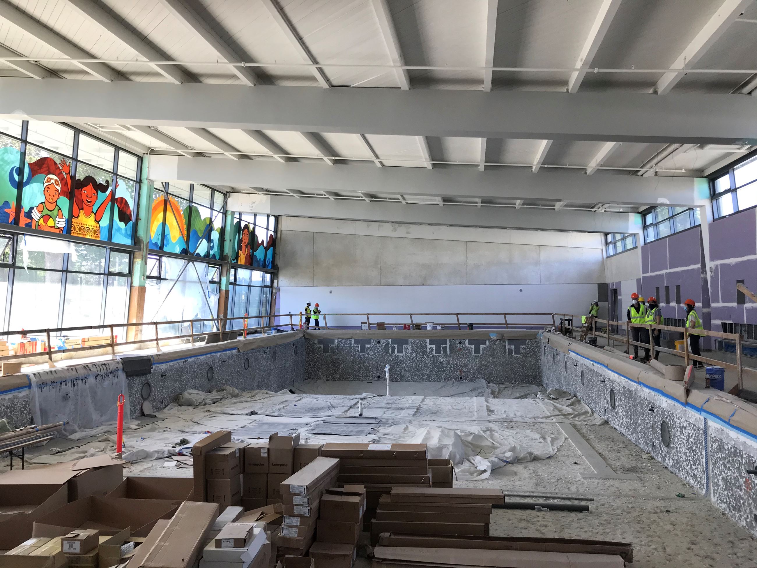 The photo shows the empty pool with construction materials sitting inside of it. The left side shows