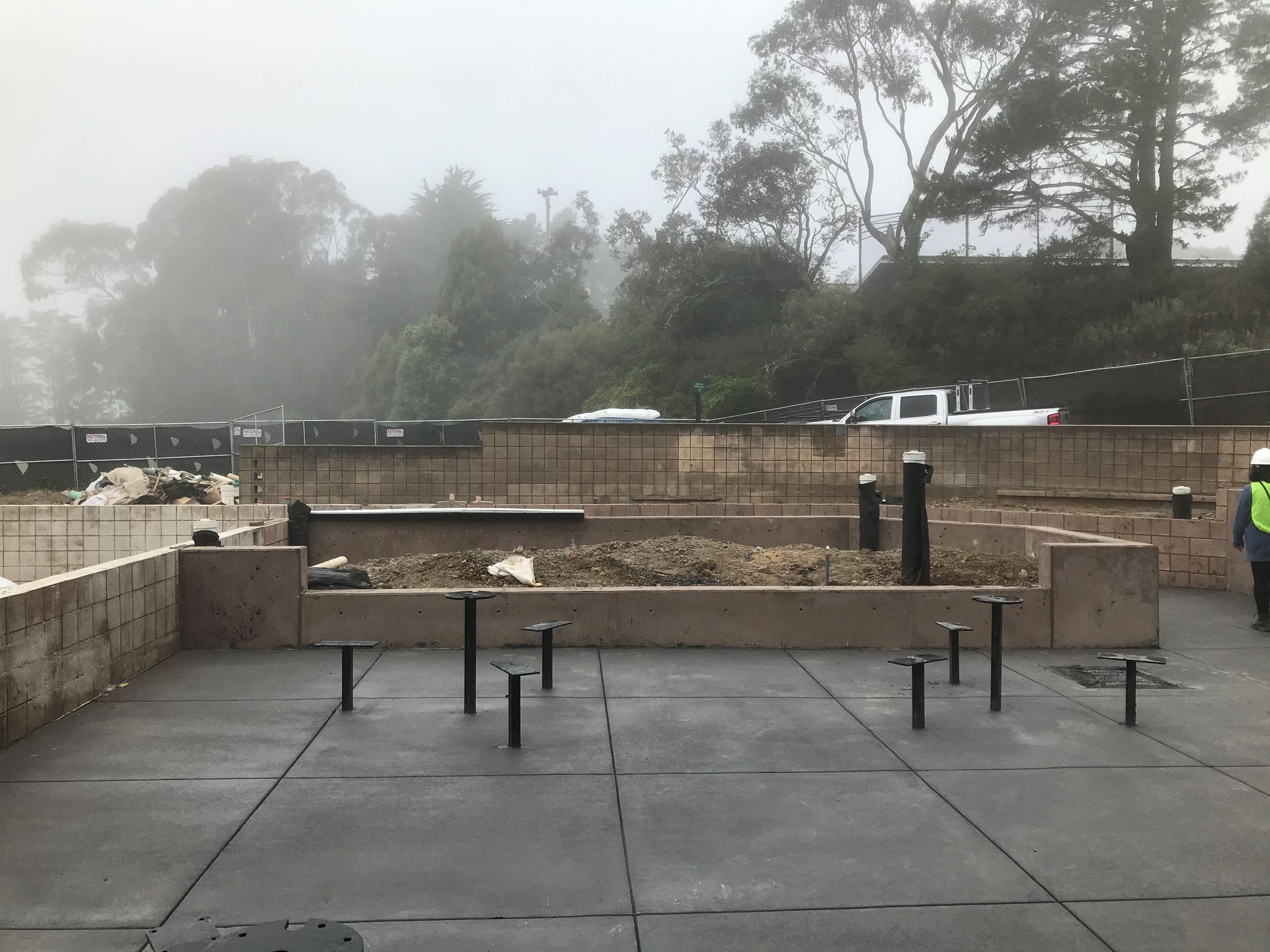 Plaza seating and table posts, cement wall planter and older brick wall