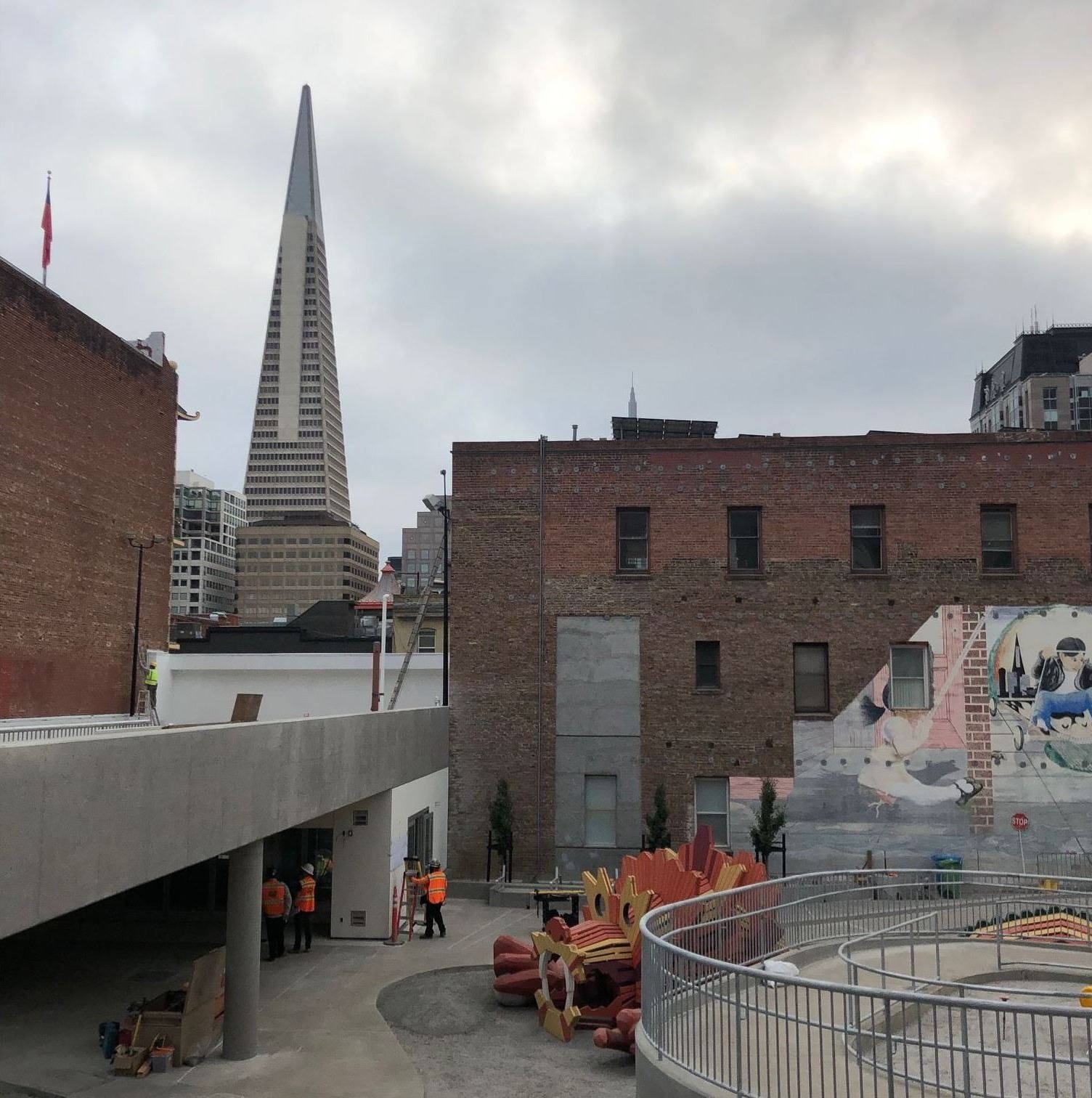 View facing the playground below with bright red dragon play equipment and cement