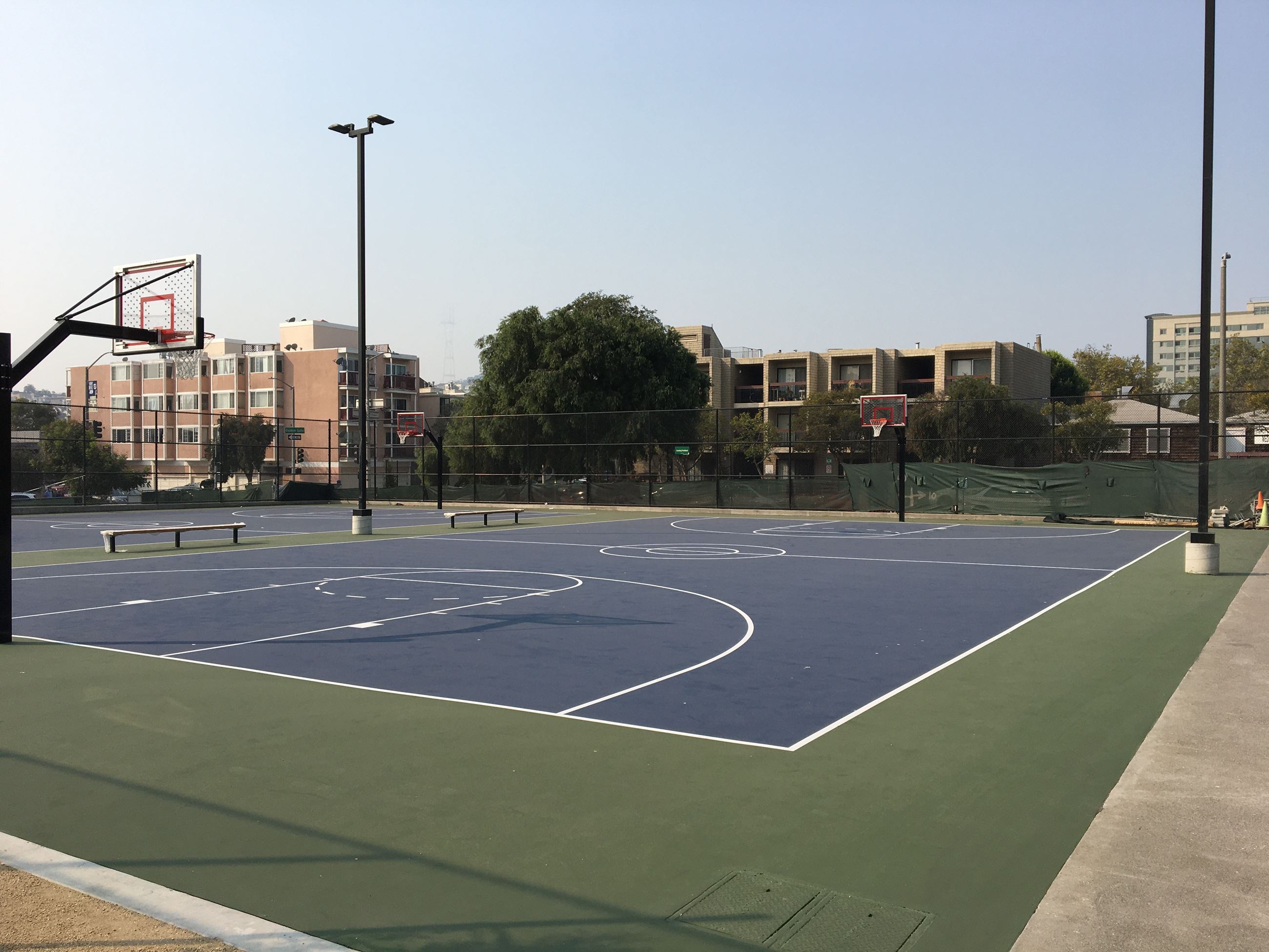 Blue basketball courts surrounded by a green perimeter with glass see through backboards