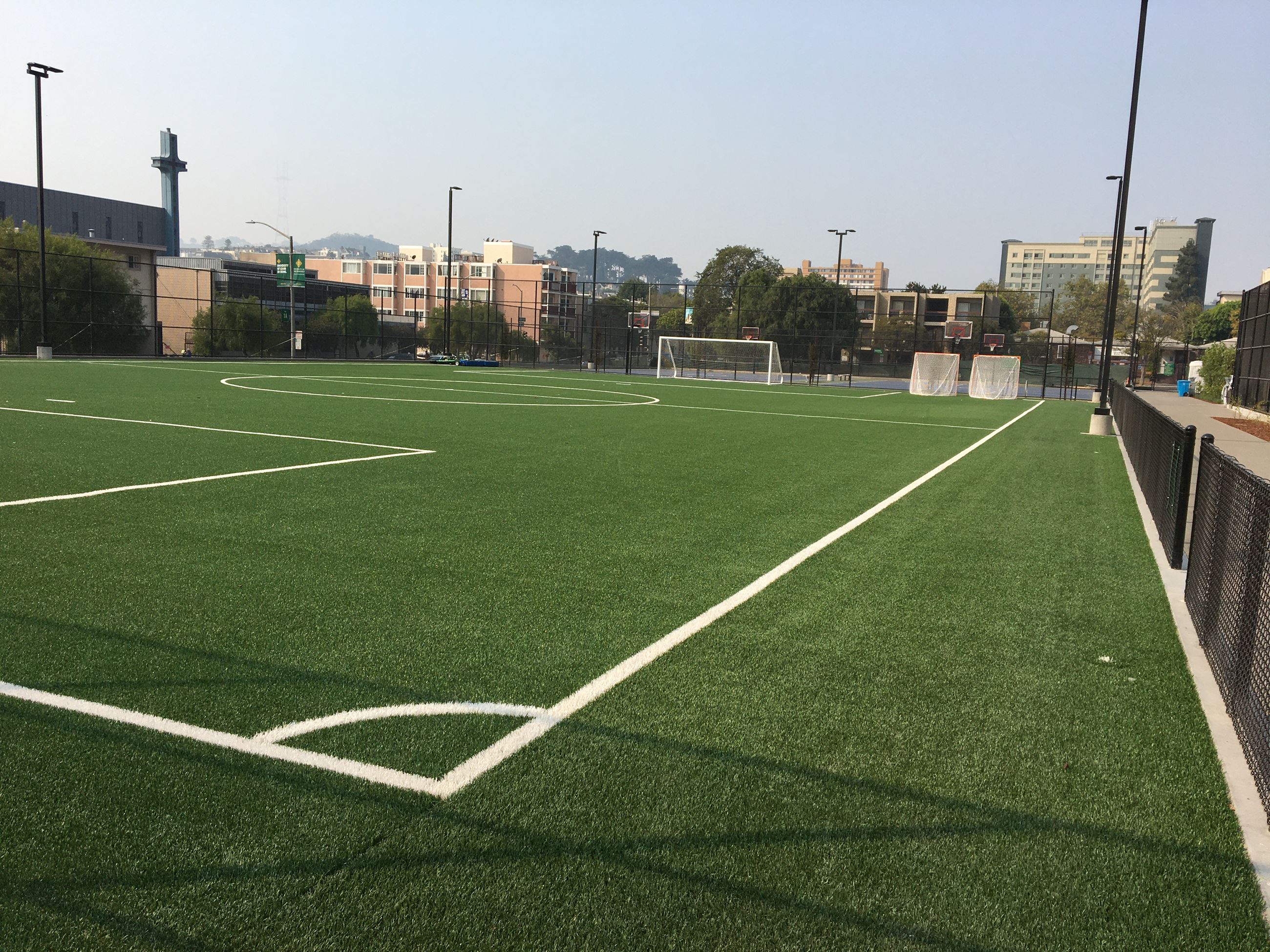 Multi purpose field with soccer goals surrounded by black coated metal fencing