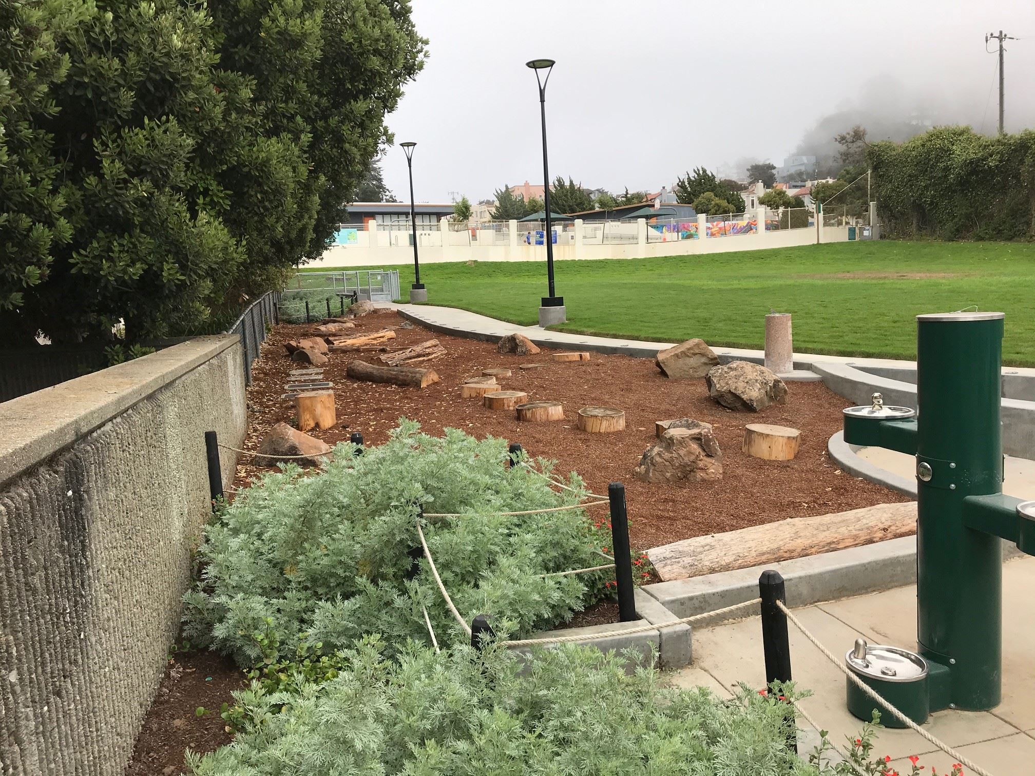 Nature exploration area with cut logs, boulders and drinking fountain