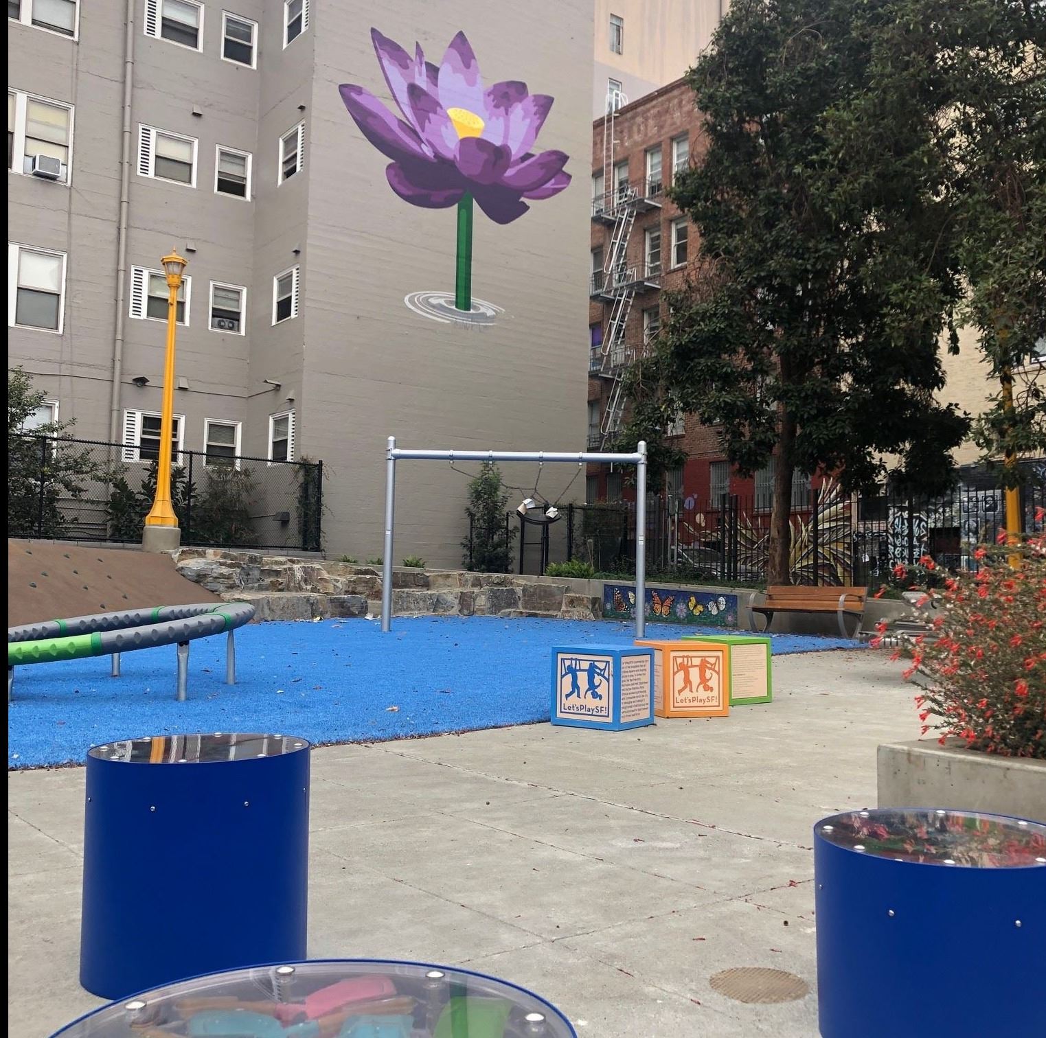 Blue circular light feature, cement, blue safety surface, swings, purple flower painted