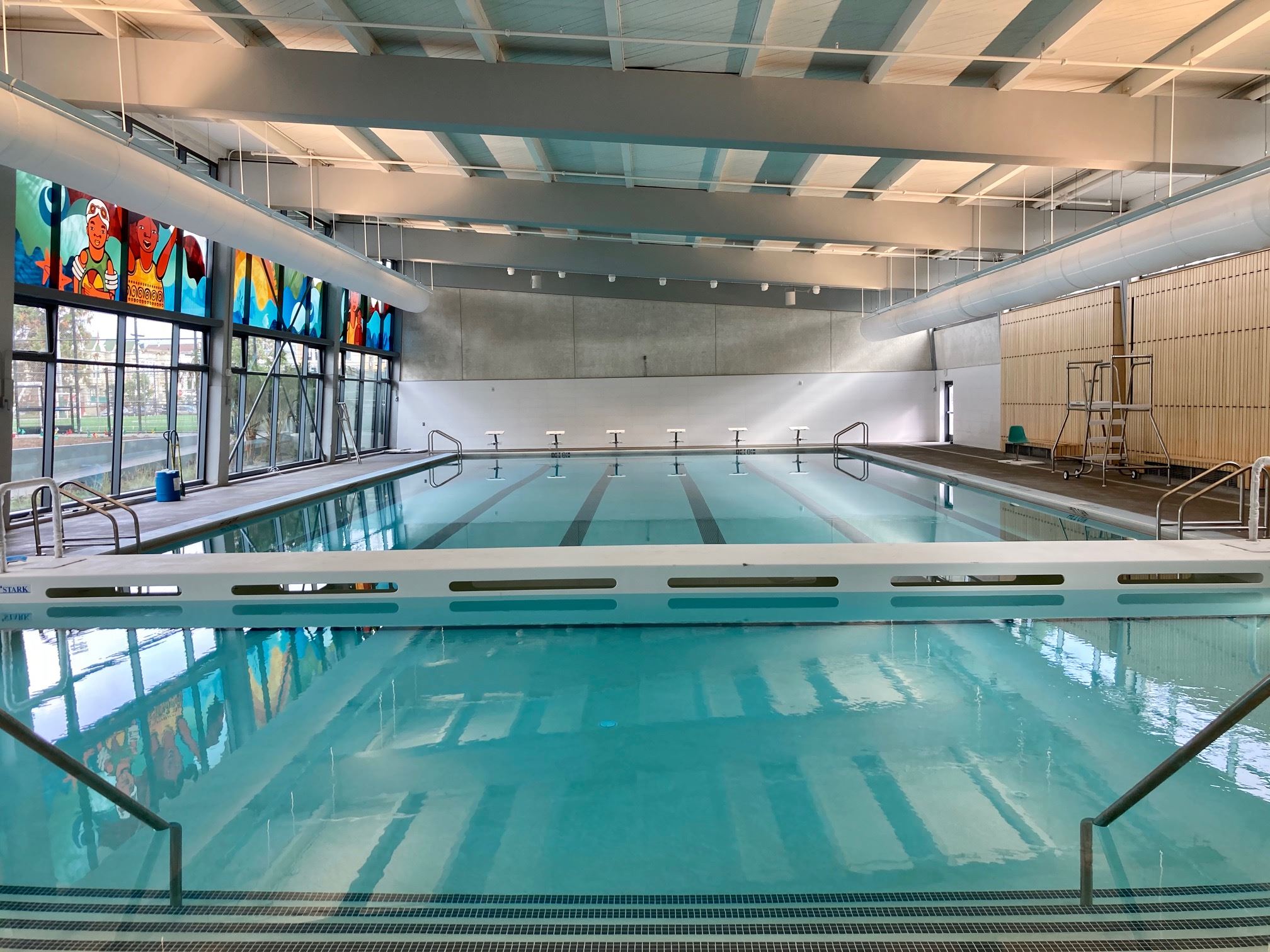 Interior of the pool building, wood slat walls, bulkhead, dive platforms, mural on glass windows