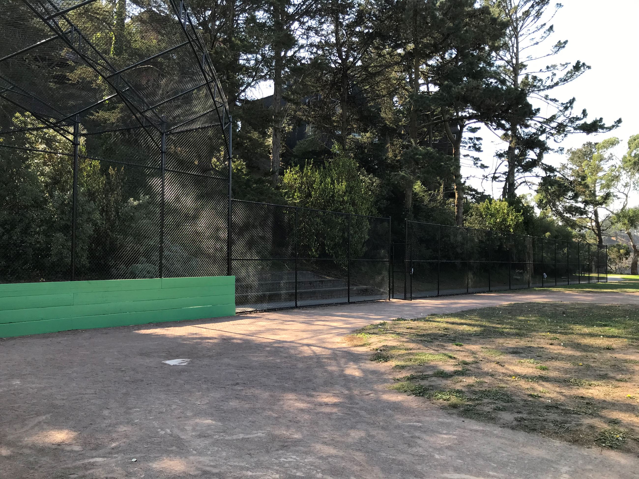 New black mesh ballfield backstop with green wood base, home plate area shown.