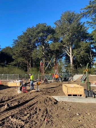 three construction workers in safety gear with various tools creating play structure tower