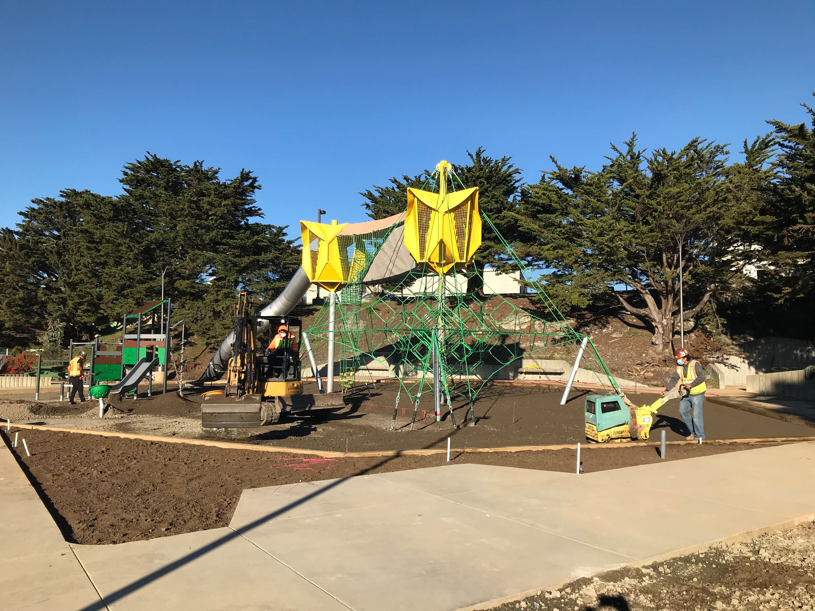 Construction workers finishing the grading below the play structure