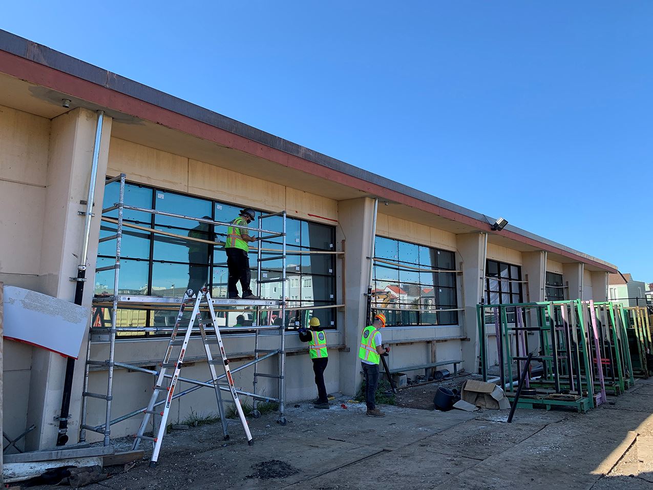 Exterior of the building with four large windows and construction workers on scaffolding.