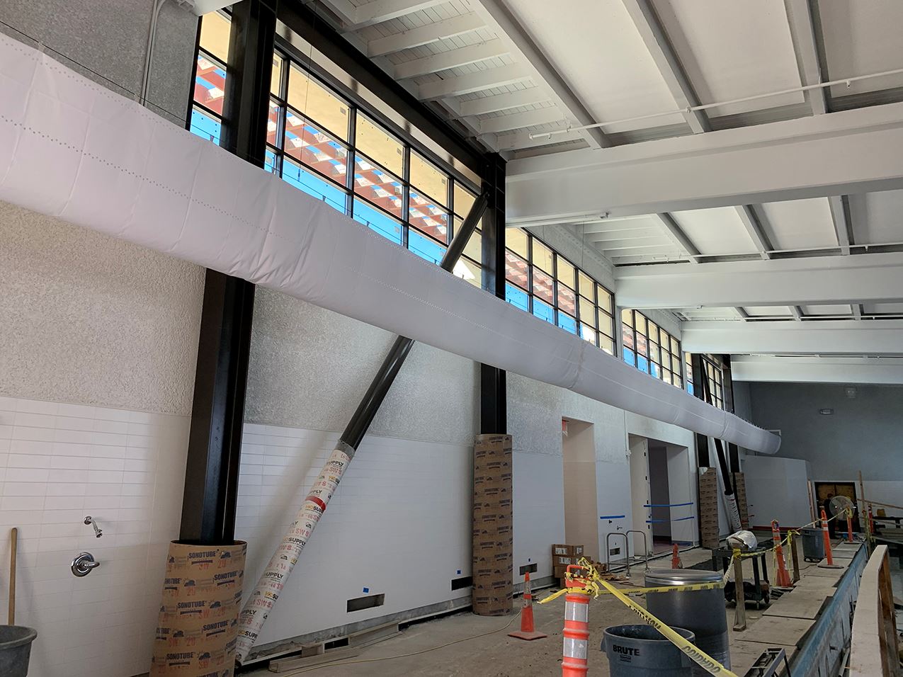 Interior of the building with four large windows, white walls and ceiling and black iron accents.