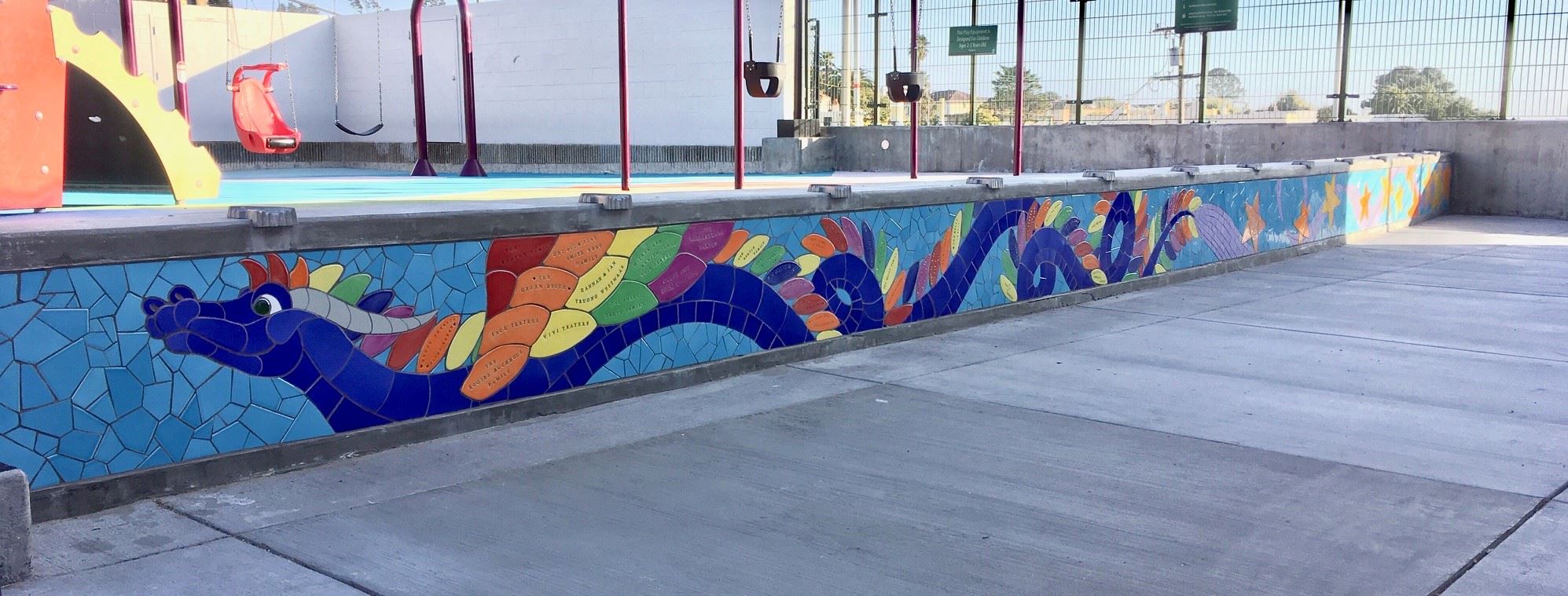 Image shows the colorful tile in a dragon shape with donor names imprinted on them.