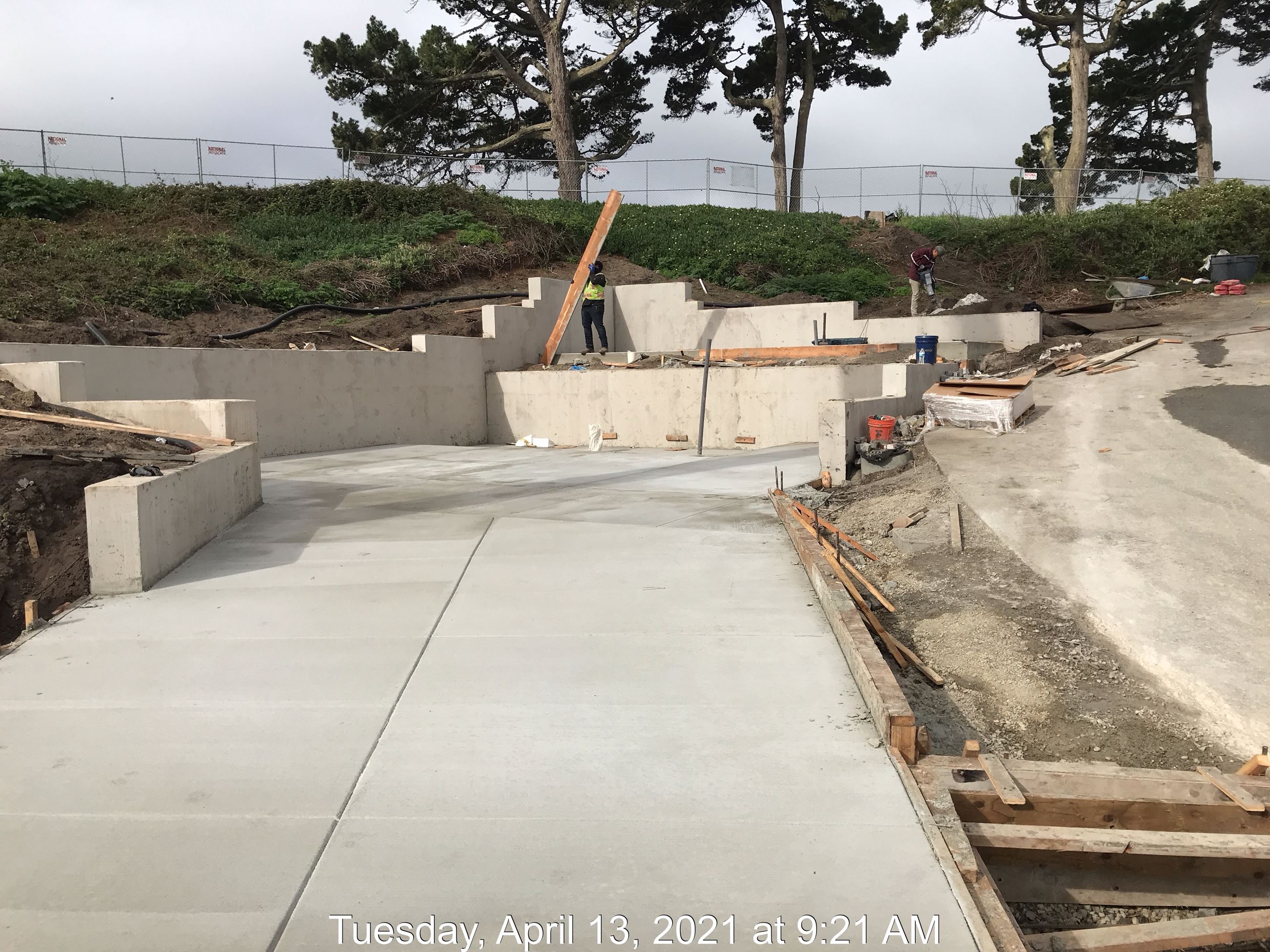 Two workers shown finishing concrete walls and pathway.