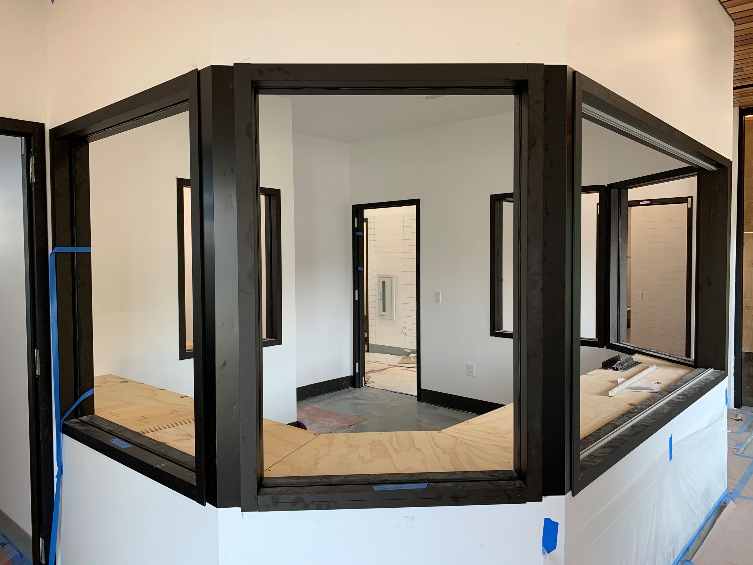 Interior front desk space with black metal framed windows and door with white walls.