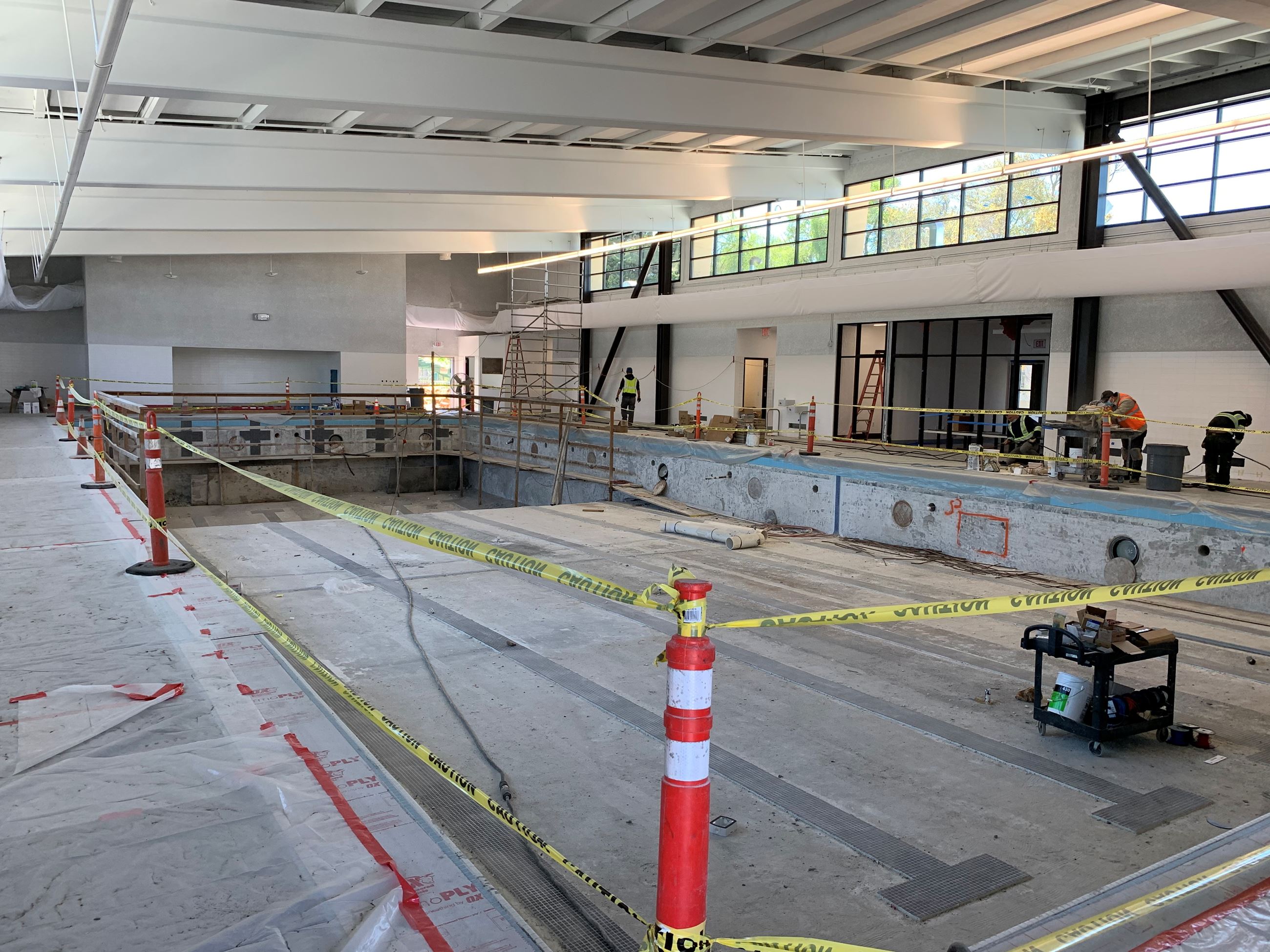 Three construction workers finishing the interior of the pool inside the main pool building