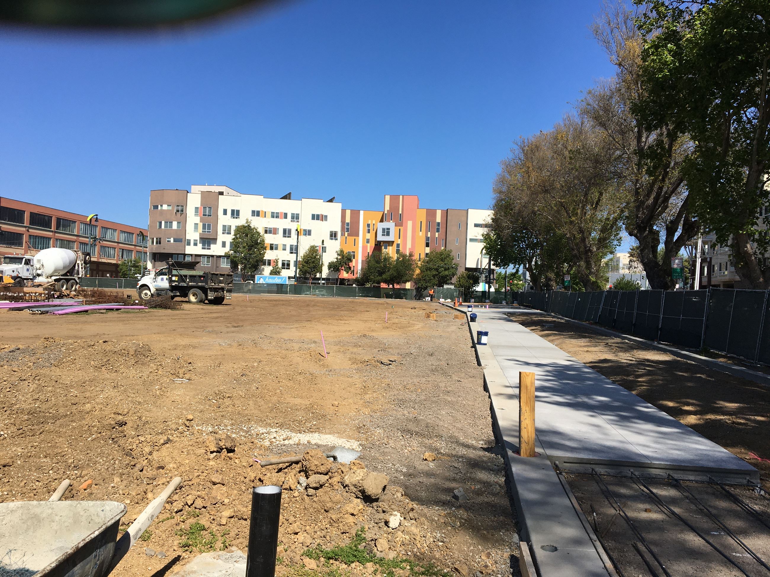 Third baseline view towards future home plate with cement pathway and exposed soil.