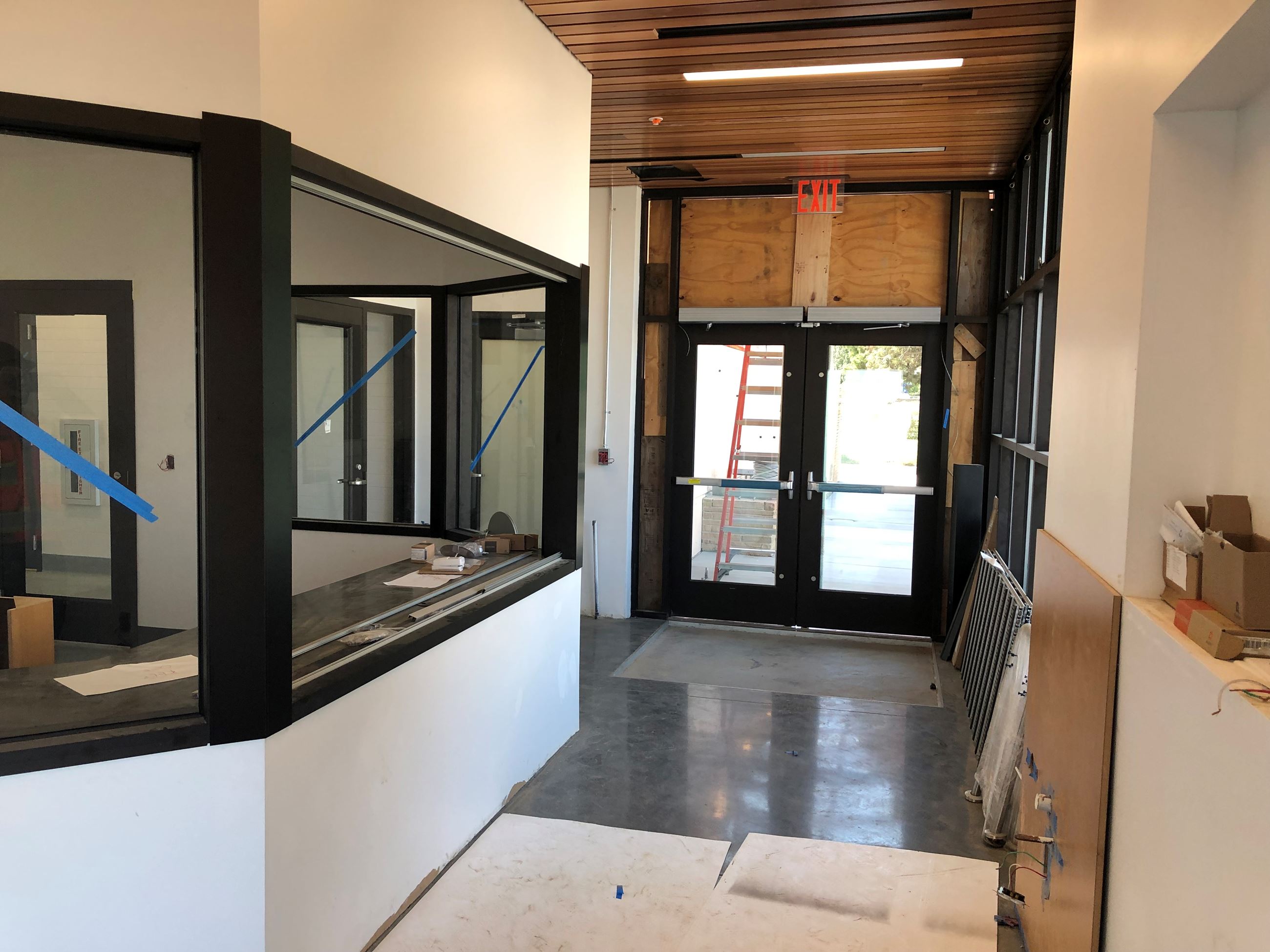 Interior entrance with black outlined windows over white walls and wood slat ceiling.