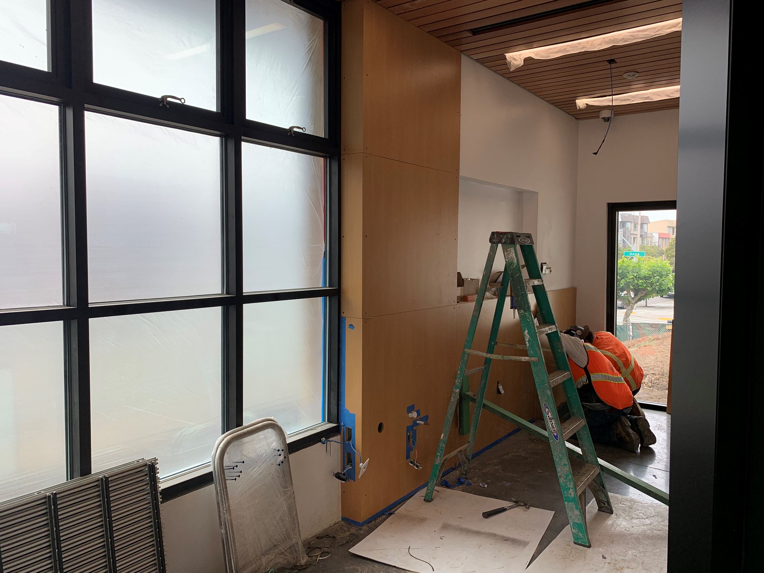 Two construction workers with orange vests completing electrical work inside the building.