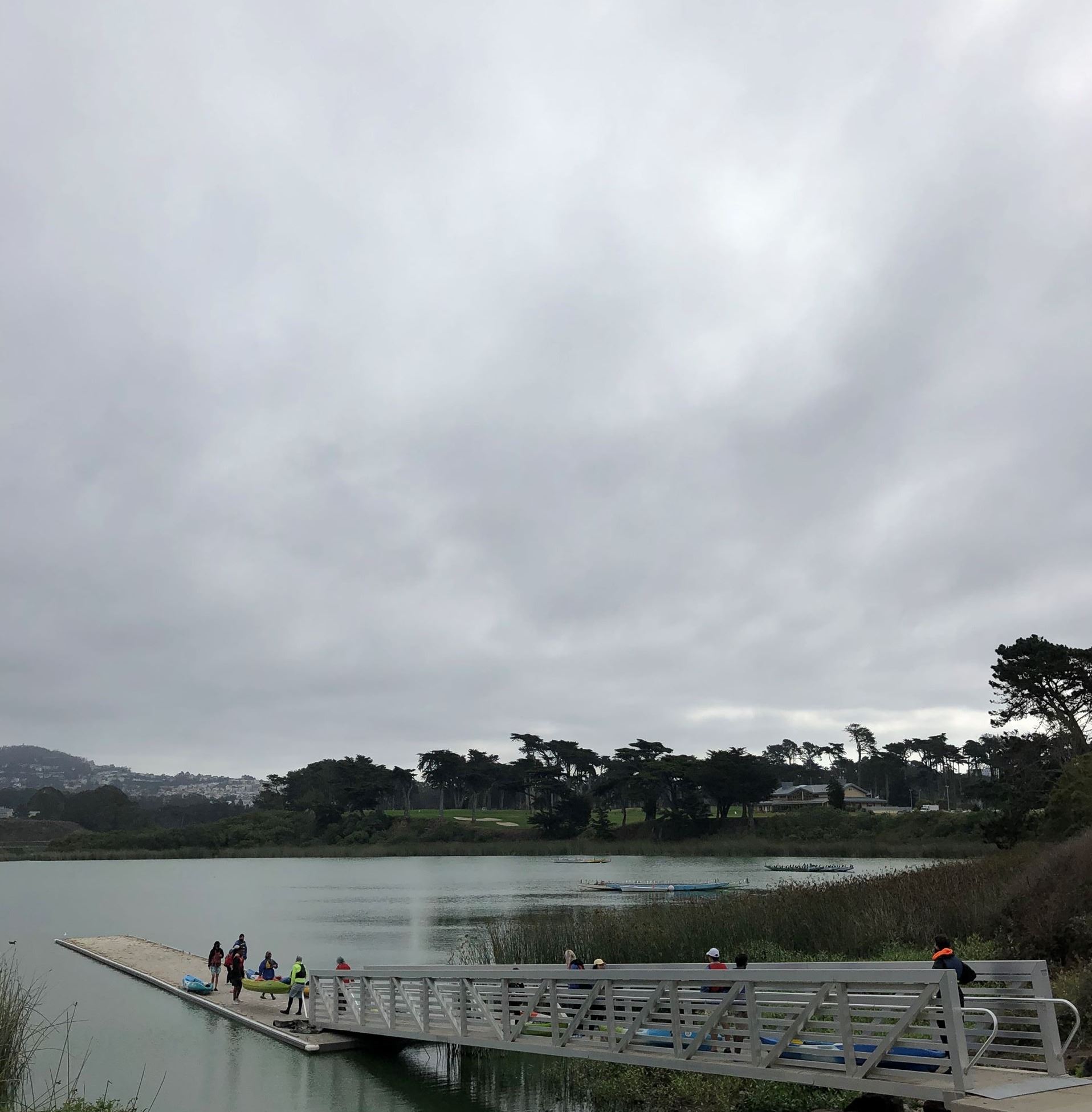 People with several blue and yellow kayaks on the dock getting ready to put their boats in the water