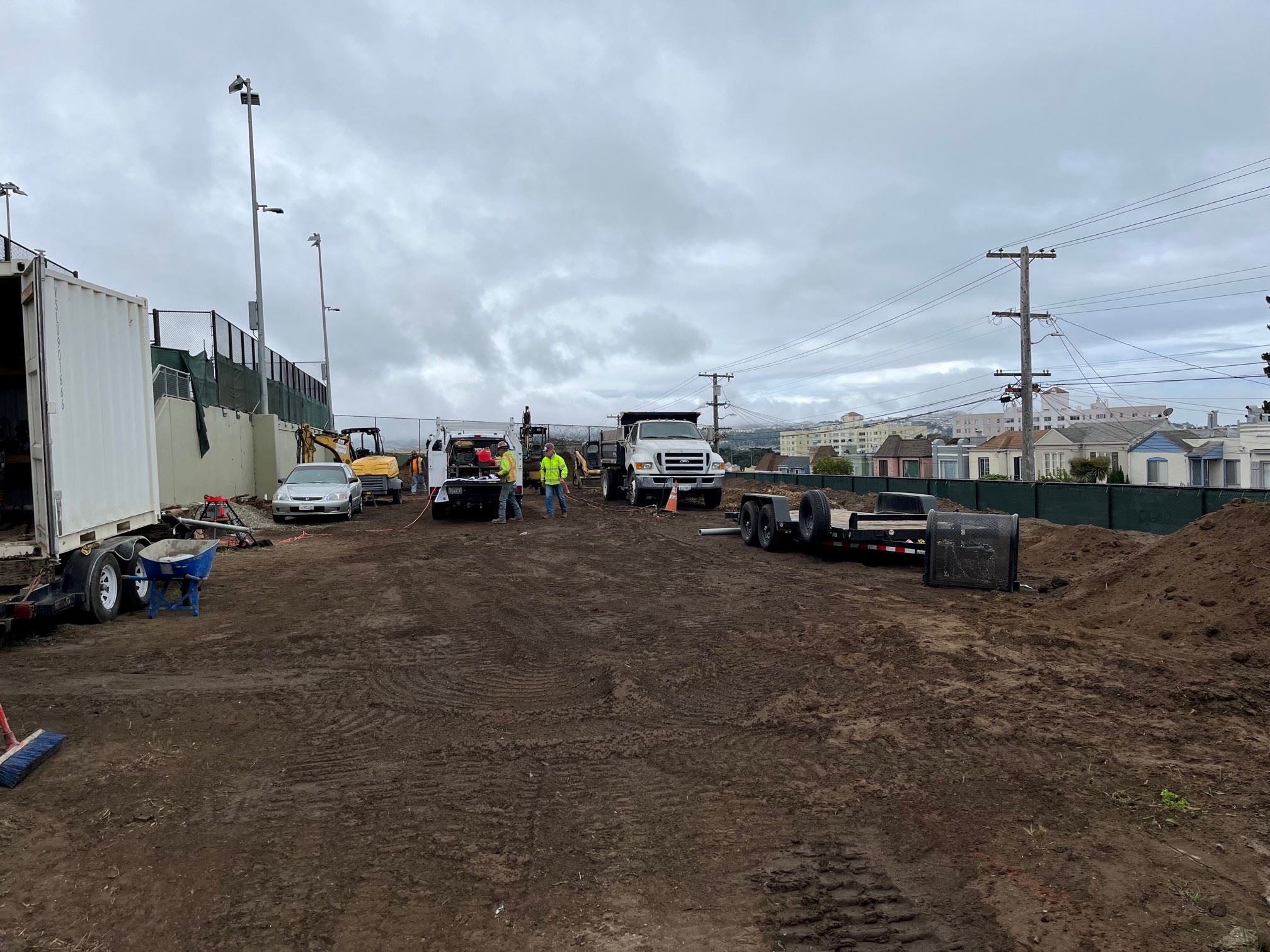 Six construction vehicles in the background in front of fresh soil