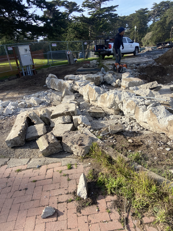 Demolished concrete in foreground with workers in the background next to a white truck
