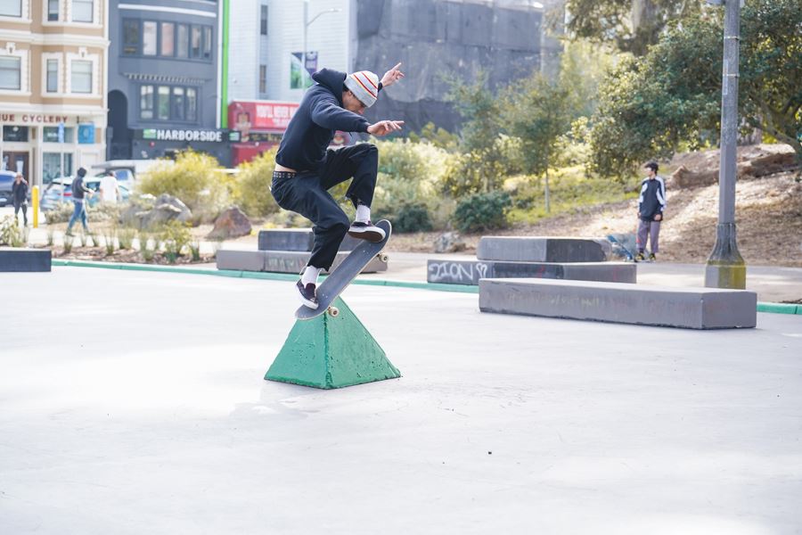 Person performing skateboard jumping trick near green pyramid element
