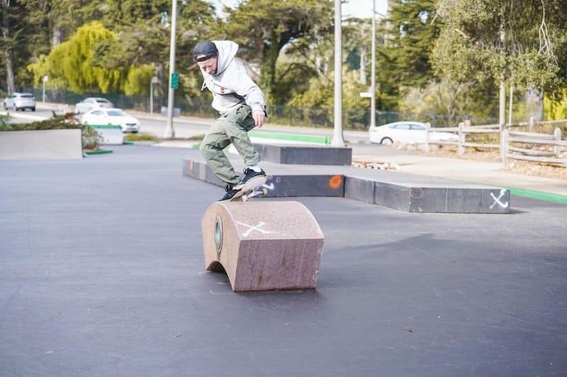 Person on skateboard jumps over small arch block element
