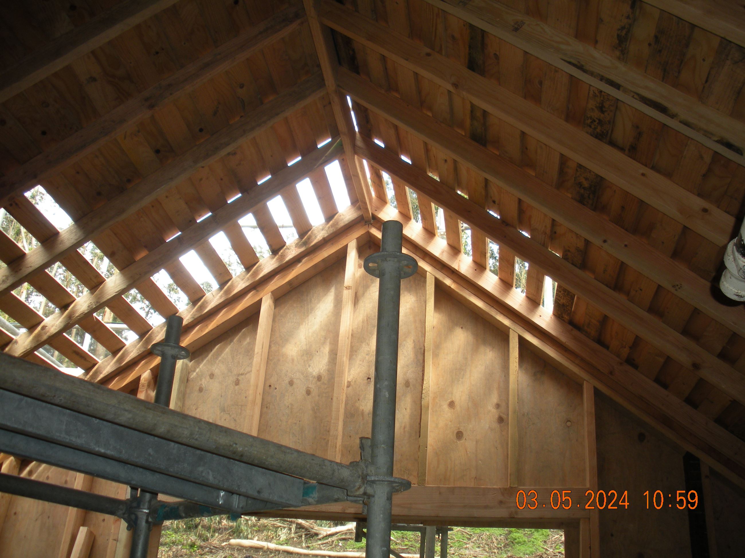 Roof framing shown from inside the building looking through the holes in the roof.