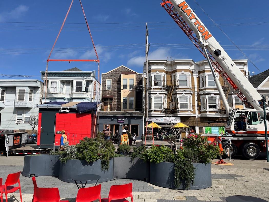 Restroom being lifted from the semi truck by a crane