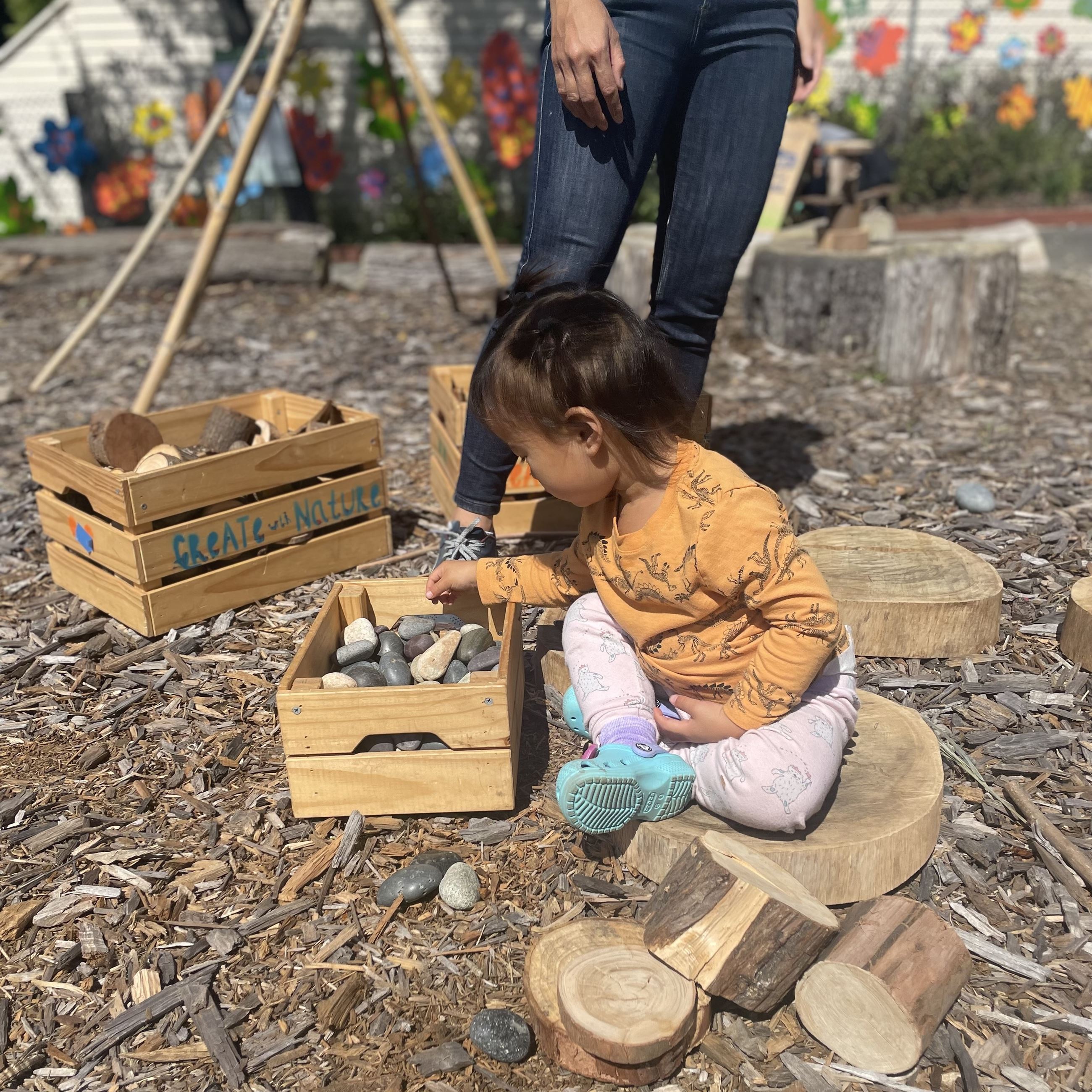 Young child plays with smooth stones in a wooden box