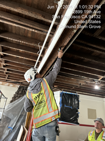 Worker reaches to exposed wood ceiling to make repairs
