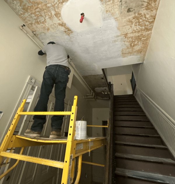 Worker on scaffolding inside entryway working on ceiling