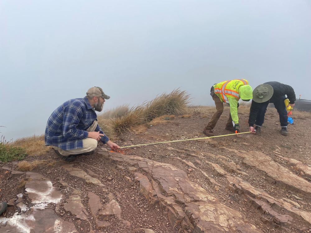 Three workers with a tape measure on the ground on a slope at Twin Peaks