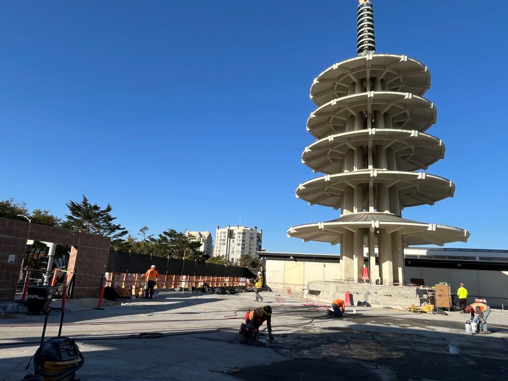 Construction workers working on concrete platform with pagoda in background