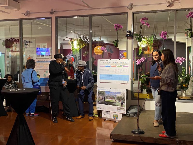 People speaking on a stage with a microphone to an audience