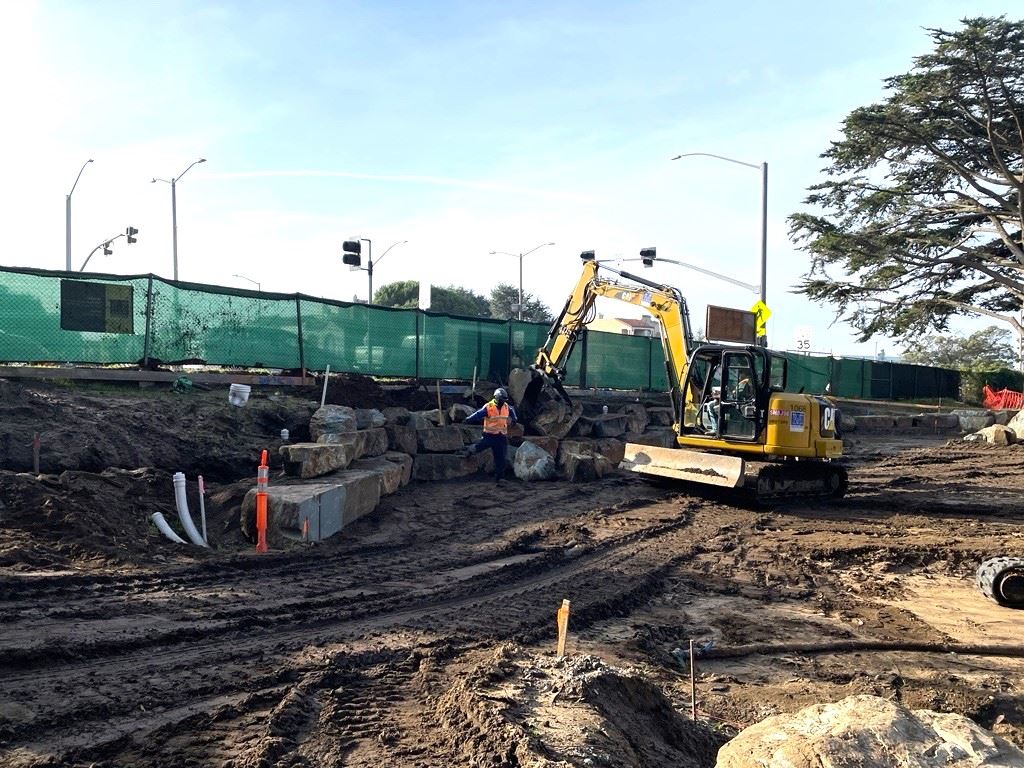 Excavator moves boulders into place