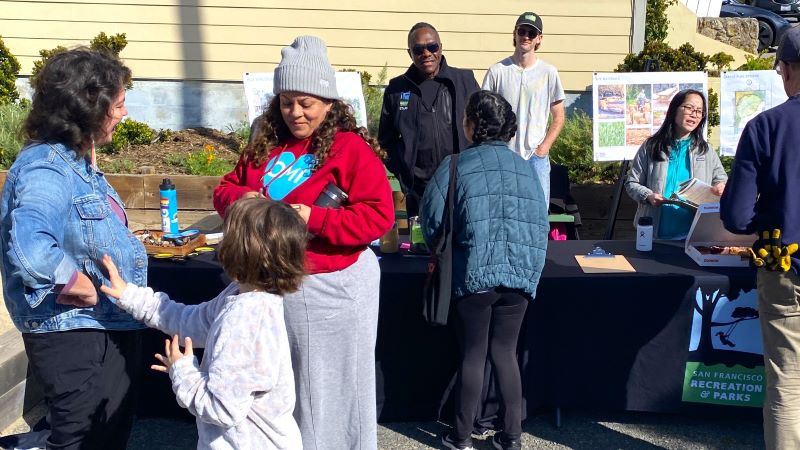 Group of people gathered around community outreach event tables
